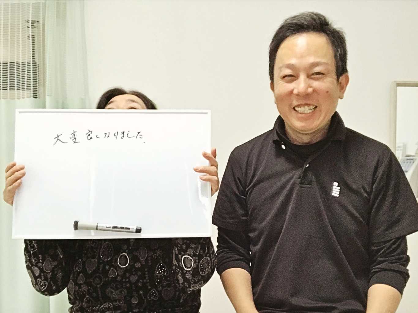 「大変良くなりました」と書かれたホワイトボードを持つ60代女性の患者様と、笑顔のはる整体院の院長