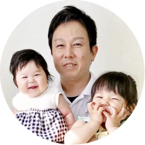 院長が笑顔の2人の幼い子どもを抱いている、丸く切り抜いた写真